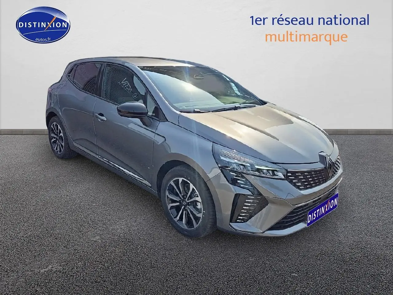 Renault Clio V gris schiste vue 3/4 avant gauche, avec jantes alu et calandre chromée visible.