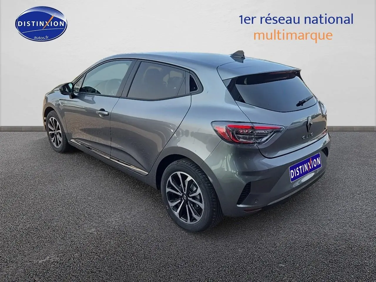 Renault Clio V gris schiste vue 3/4 arrière droit, jantes alu et vitres arrière surteintées visibles.