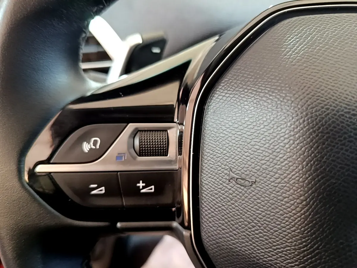 Gros plan sur les commandes gauche du volant cuir noir du Peugeot 3008 hybride rechargeable 2021.