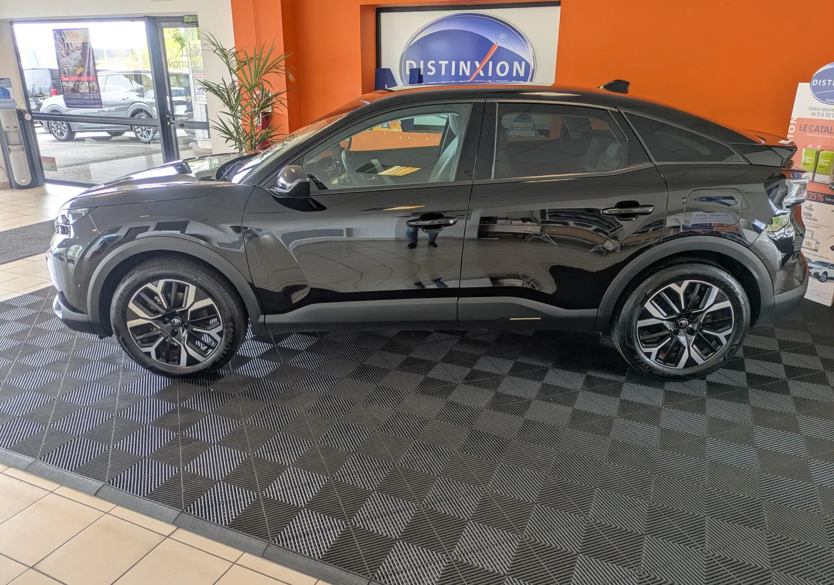 Vue latérale gauche d'une Citroën C4 noire 2025 hybride, avec jantes bi-ton et toit plongeant en concession.