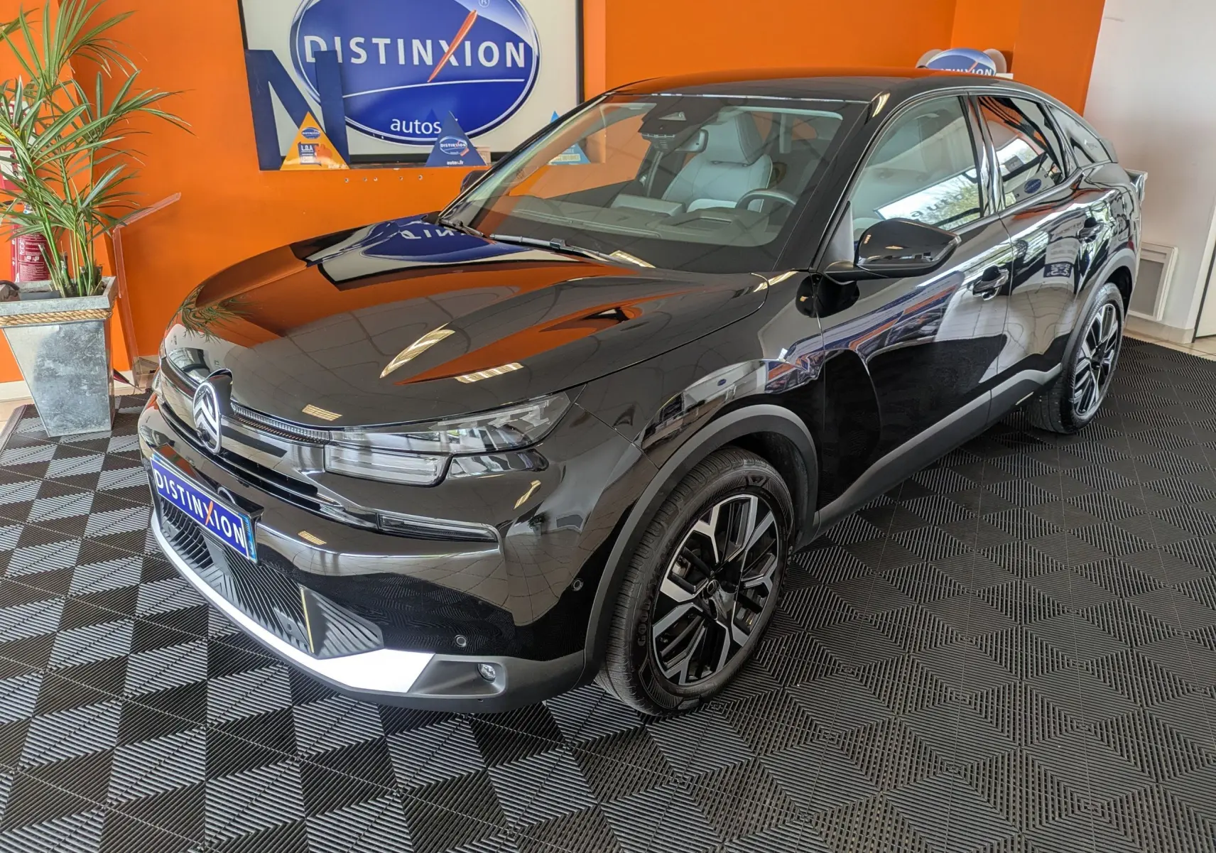 Citroën C4 noir vue 3/4 avant droit en intérieur, avec jantes bi-ton et calandre distinctive.