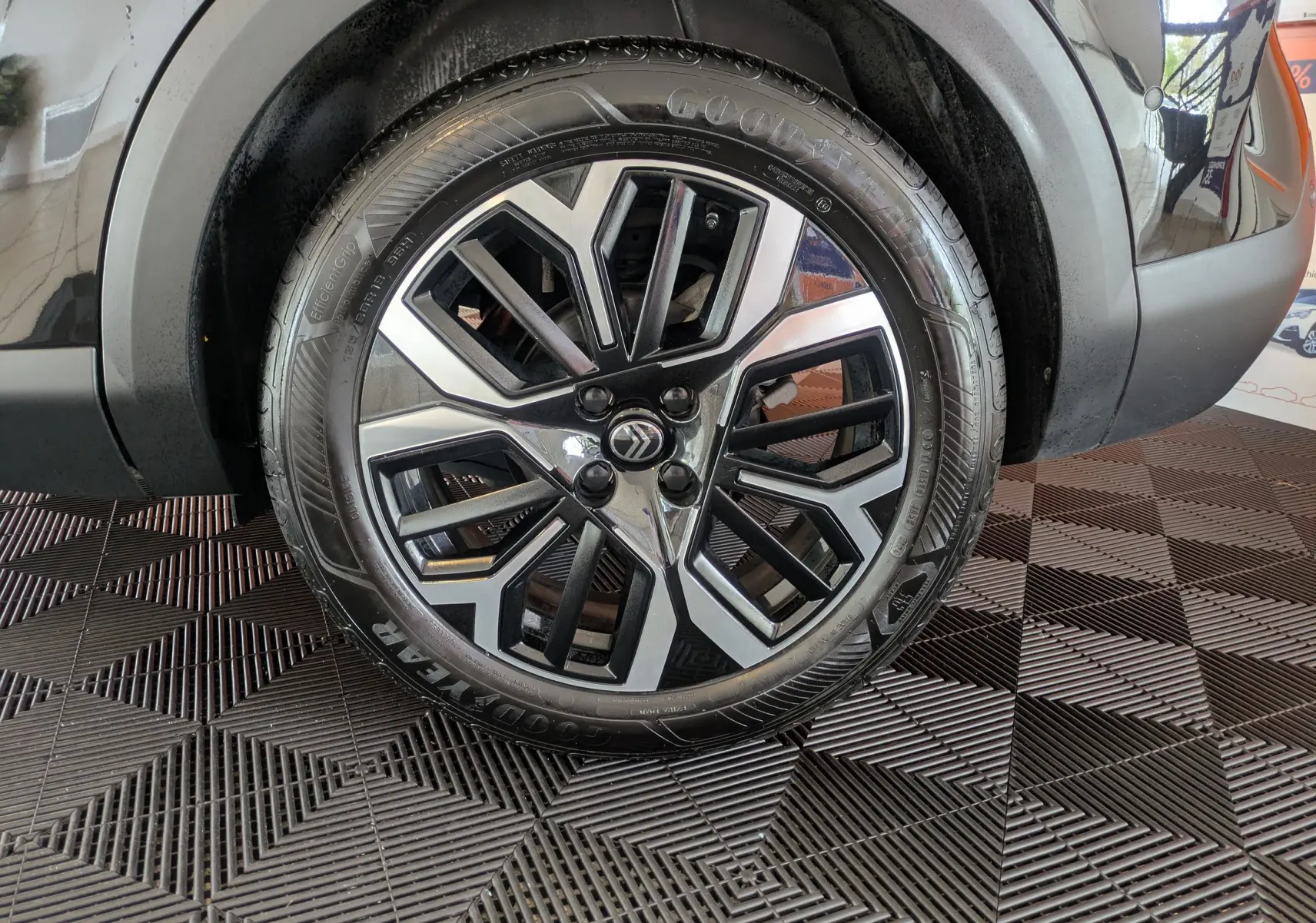 Gros plan sur la roue avant droite noire d'une Citroën C4 1.2 Hybride 136ch avec jante alliage bicolore design.