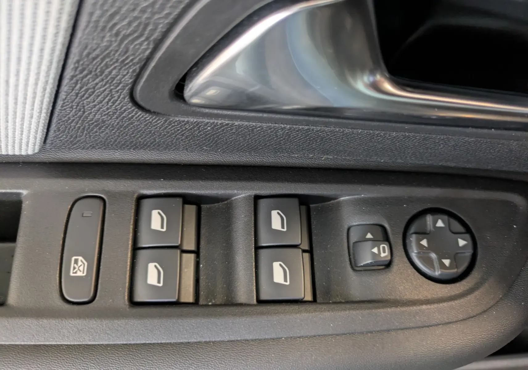 Gros plan sur les commandes des vitres électriques et réglages des rétroviseurs côté conducteur d'une Citroën C4 noire.