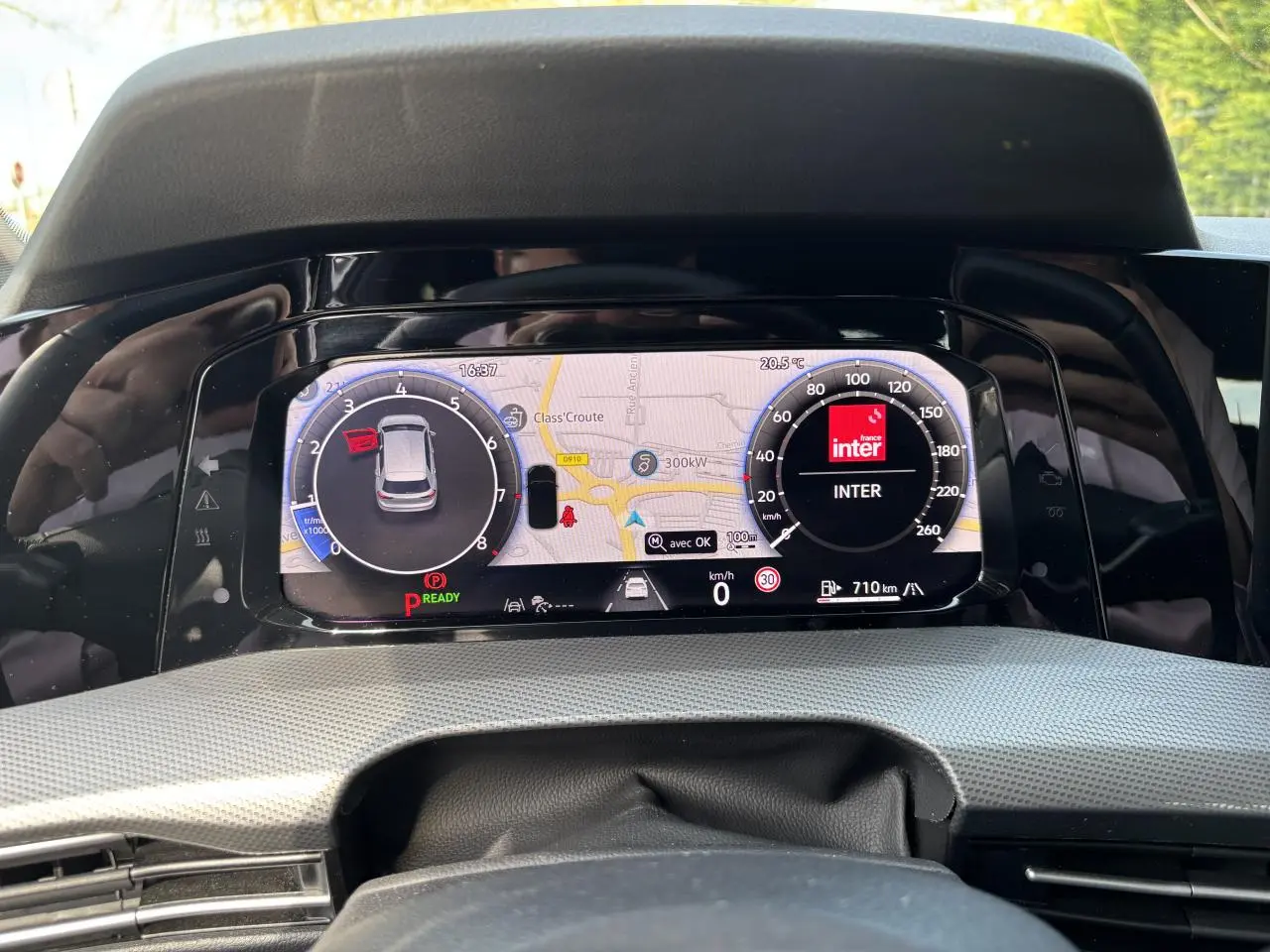 Vue rapprochée du tableau de bord numérique de la Volkswagen Golf blanche 2024, affichant la navigation et la radio.