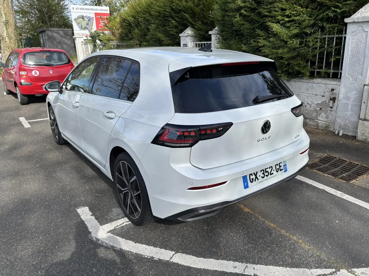 Vue 3/4 arrière droite d'une Volkswagen Golf blanche 2024 avec feux arrière LED et jantes noires en alliage.