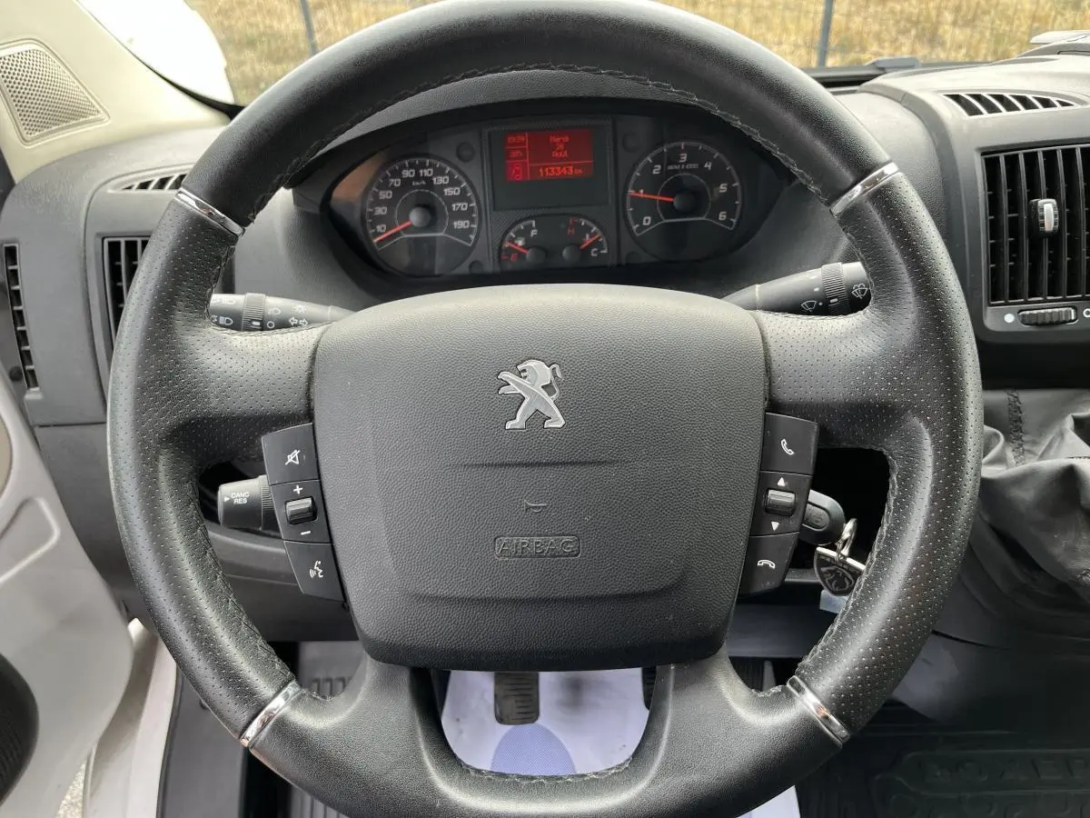 Vue rapprochée du volant en cuir noir du Peugeot Boxer Fourgon 2023 avec tableau de bord et compteur digital rouge.