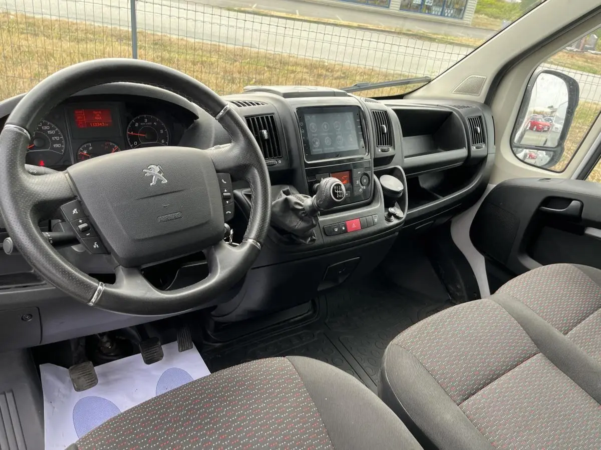 Vue intérieure côté conducteur du Peugeot Boxer Fourgon 2023, tableau de bord noir avec volant cuir et console centrale tactile.