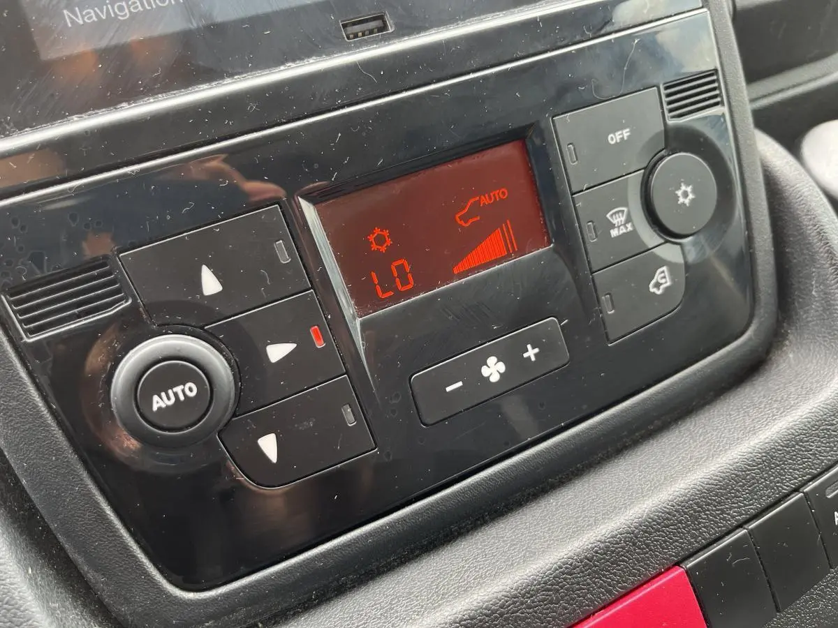 Détail du panneau de commande de la climatisation automatique du Peugeot Boxer Fourgon blanc, affichage rouge et boutons noirs.