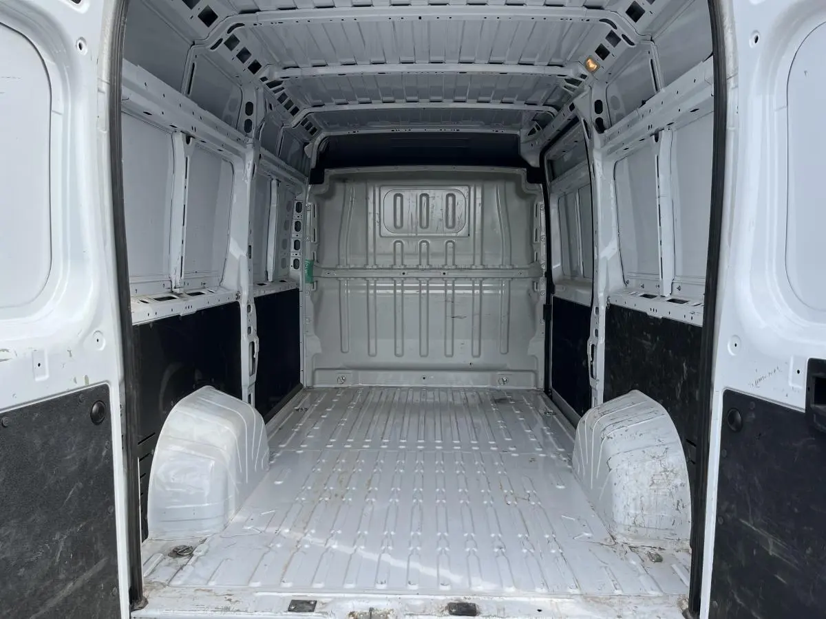Vue intérieure arrière du fourgon Peugeot Boxer blanc, montrant l'espace de chargement tôlé et les protections latérales noires.