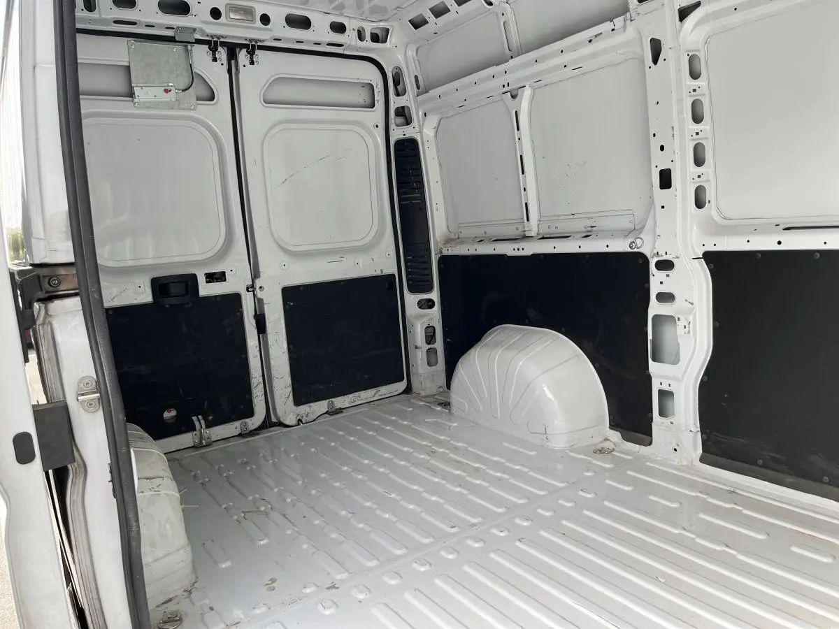 Vue intérieure arrière du Peugeot Boxer Fourgon blanc, montrant l'espace de chargement tôlé avec panneaux noirs.