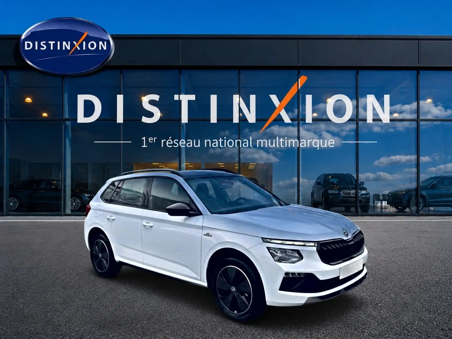 Vue 3/4 avant droite d'un Skoda Kamiq blanc nacré avec toit noir et jantes alliage noires devant un showroom Distinxion.