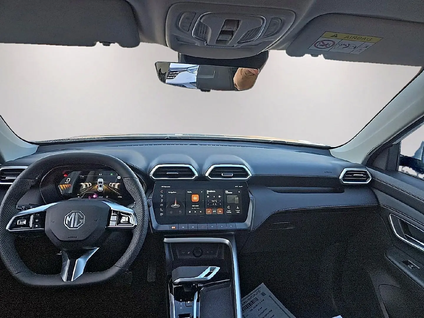 Vue frontale de l’habitacle noir du MG Motor ZS 1.5 hybrid 197 luxury avec écran tactile central et volant multifonction.