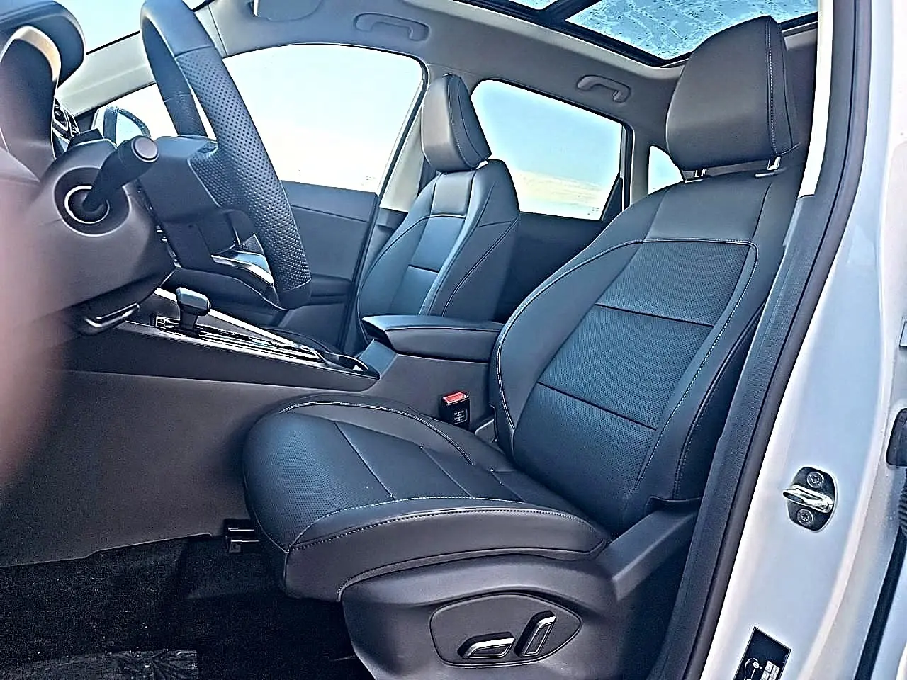 Vue intérieure côté conducteur du MG Motor ZS blanc 2026, sièges en similicuir noir avec toit panoramique en verre.
