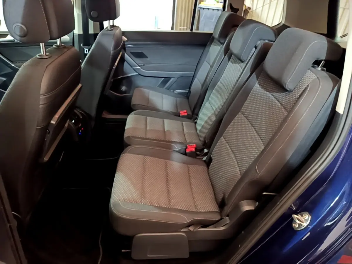 Vue latérale des sièges arrière gris foncé du Volkswagen Touran bleu 2021, montrant trois places individuelles.