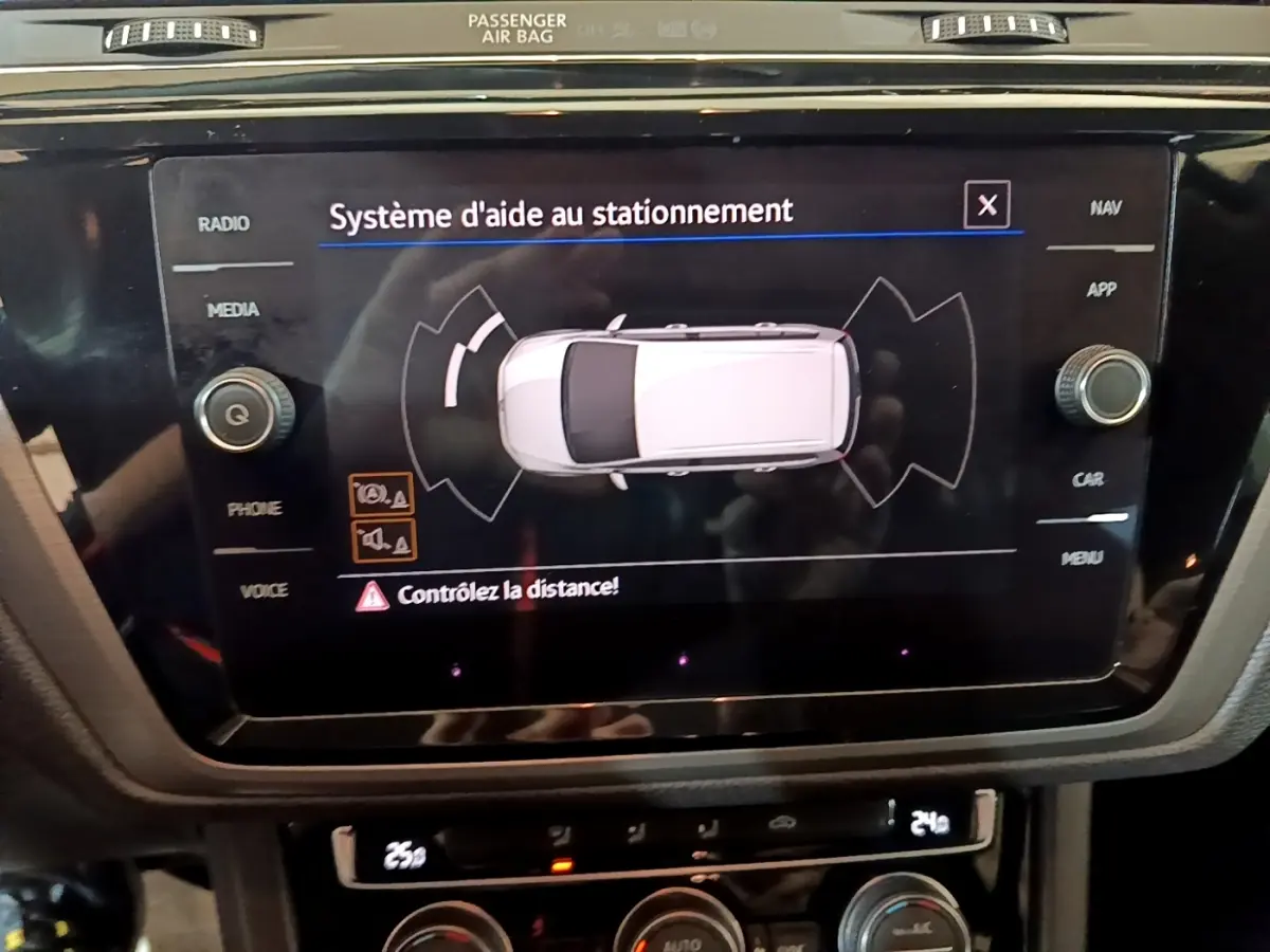 Écran tactile central affichant le système d'aide au stationnement du Volkswagen Touran 1.5 TSI bleu, vue intérieure console centrale.