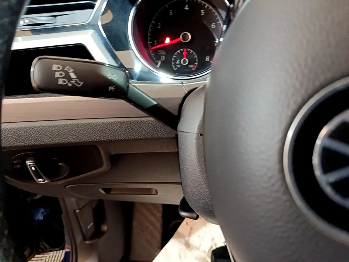 Gros plan sur le volant et le commodo gauche du tableau de bord d'un Volkswagen Touran bleu 2021.