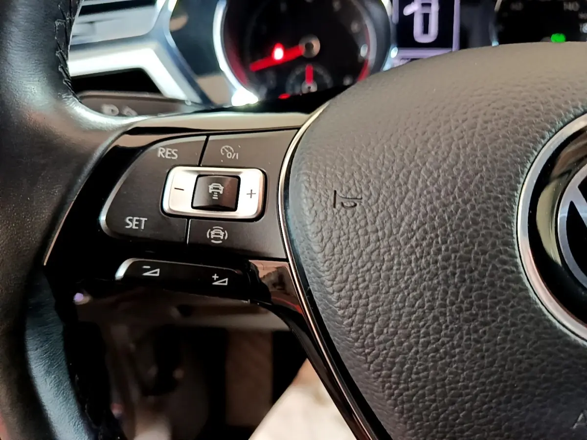 Gros plan sur le volant cuir gris du Volkswagen Touran 2021 avec commandes intégrées au côté gauche.