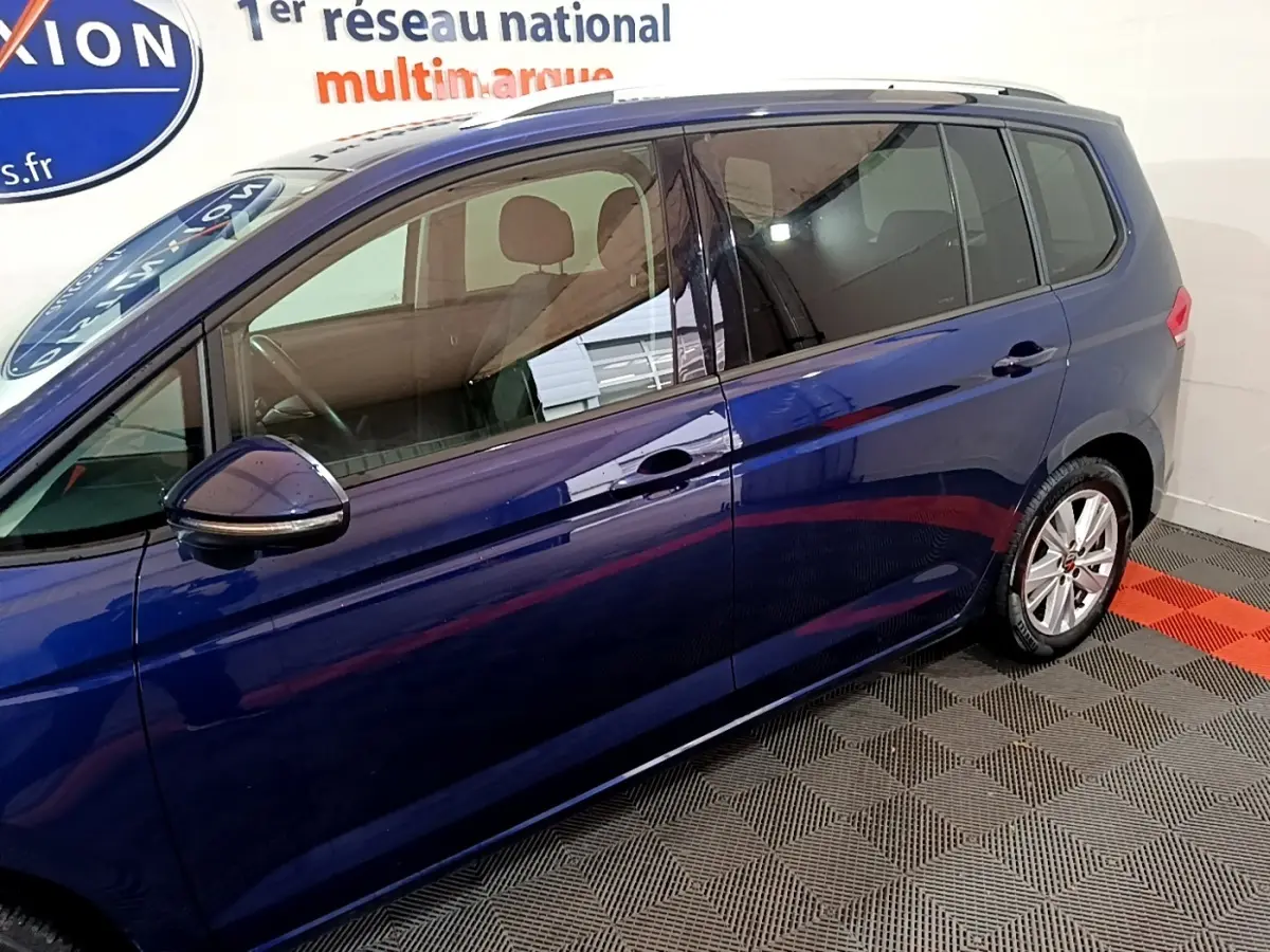 Vue latérale côté gauche d'un Volkswagen Touran bleu 2021 avec vitres teintées et jantes alliage.