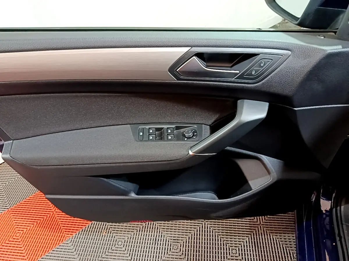 Intérieur côté gauche de la porte d'une Volkswagen Touran bleu 2021, avec commandes de vitres et poignée argentée.
