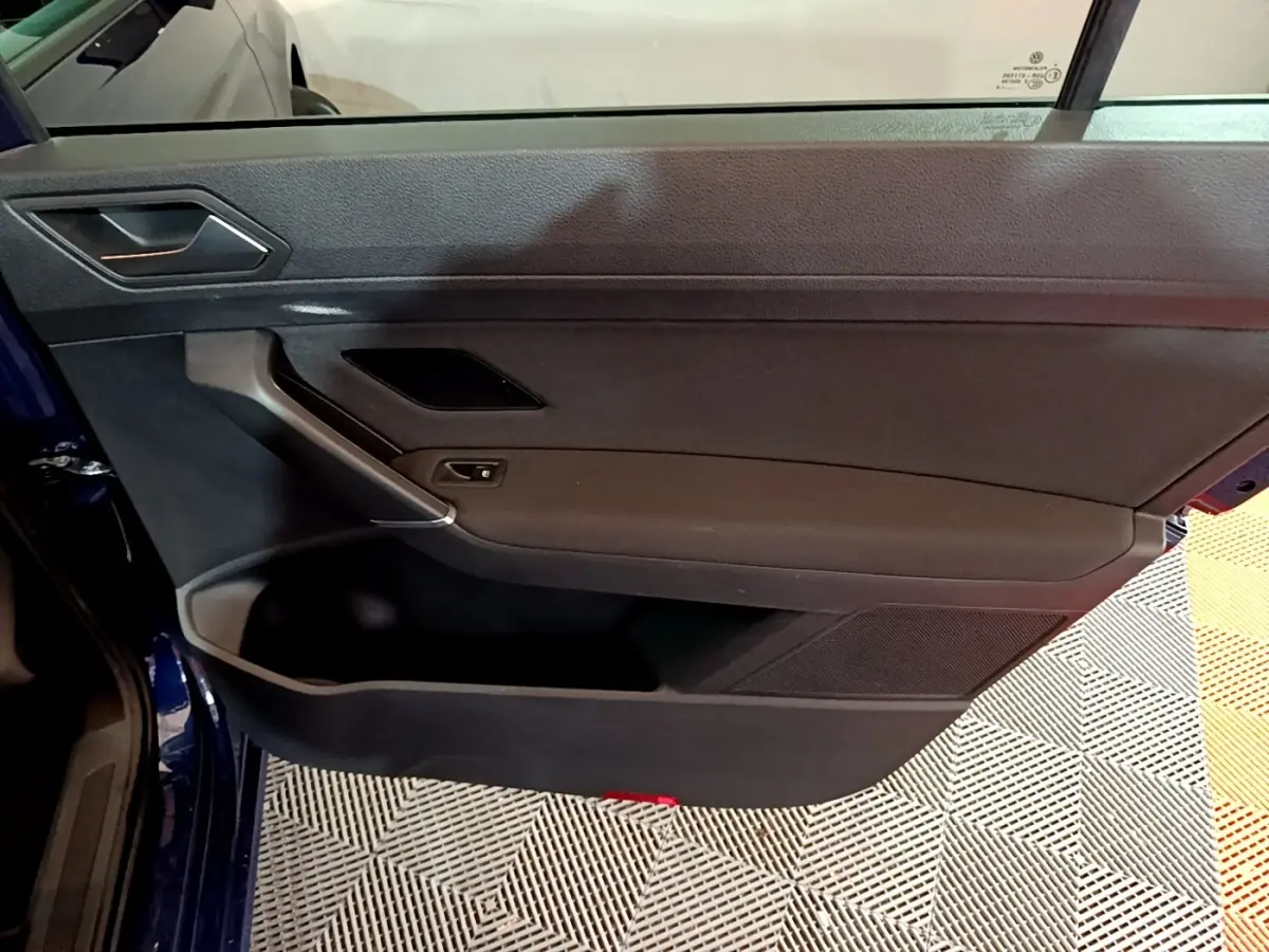 Porte intérieure côté gauche noire du Volkswagen Touran bleu 3/4 avant, avec poignée et haut-parleur intégrés.