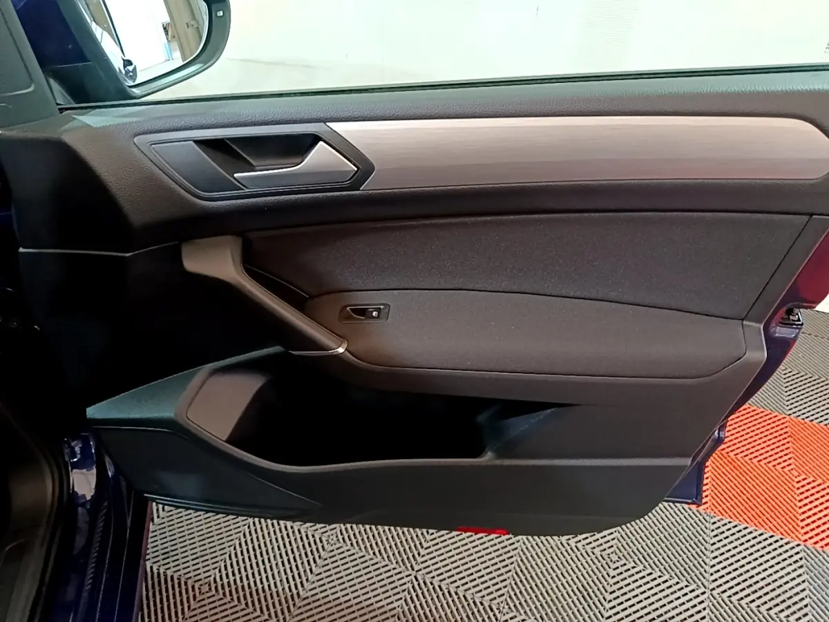 Porte côté gauche ouverte d’un Volkswagen Touran bleu 2021, intérieur noir avec insert décoratif gris.