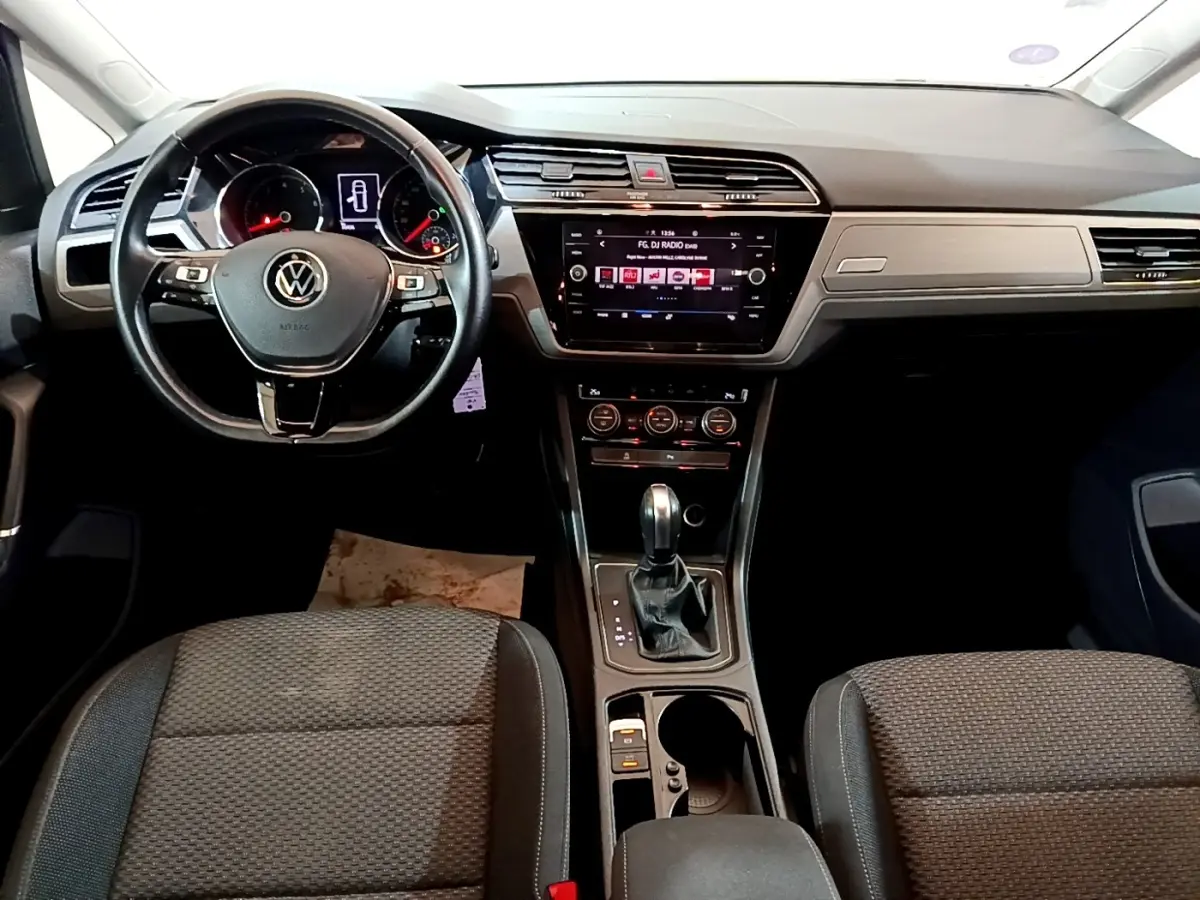 Intérieur Volkswagen Touran 2021, vue frontale du tableau de bord avec écran tactile et volant multifonctions noir.