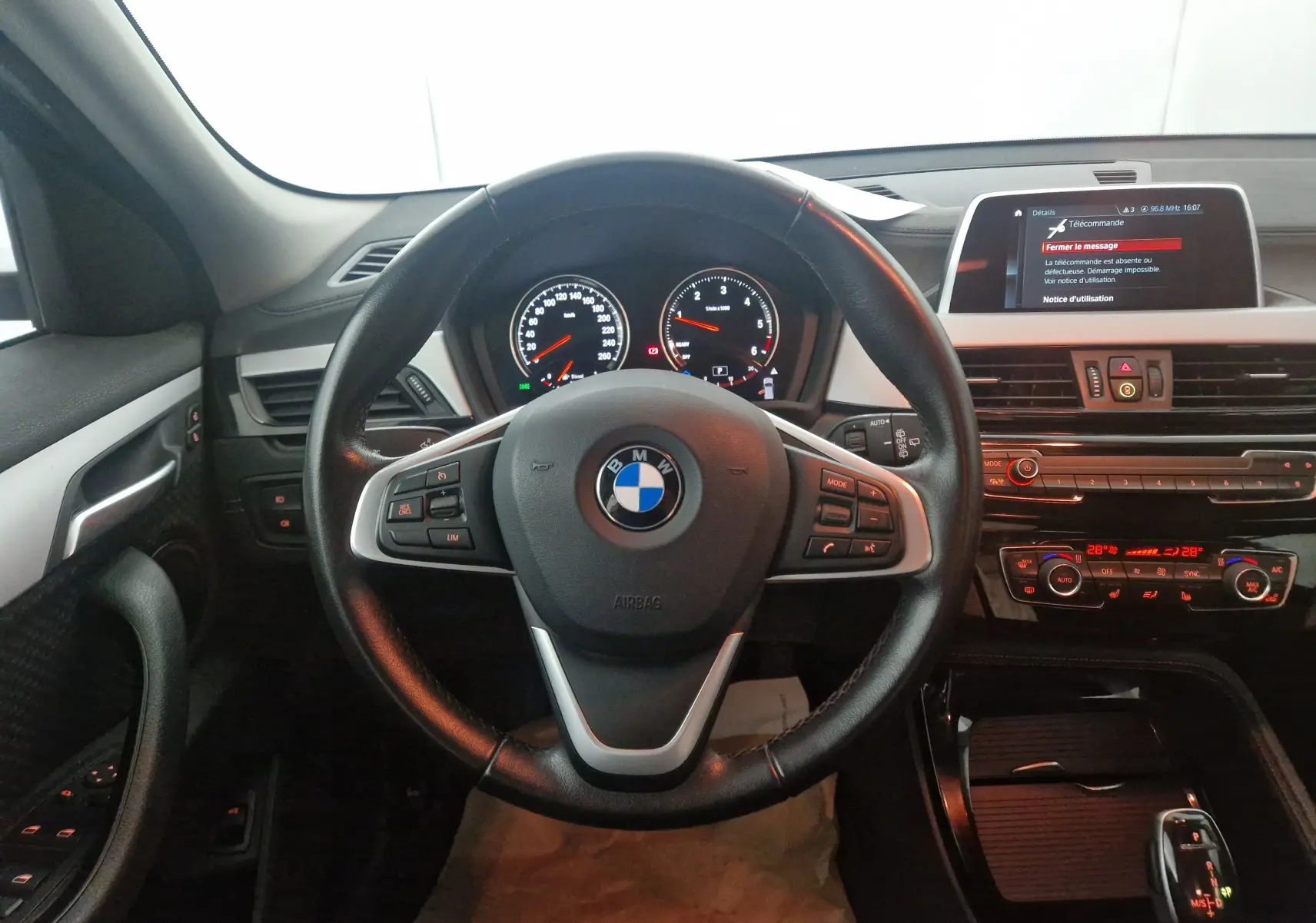 Vue intérieure centrée sur le volant noir de la BMW X2 2018, avec tableau de bord et écran multimédia visibles.