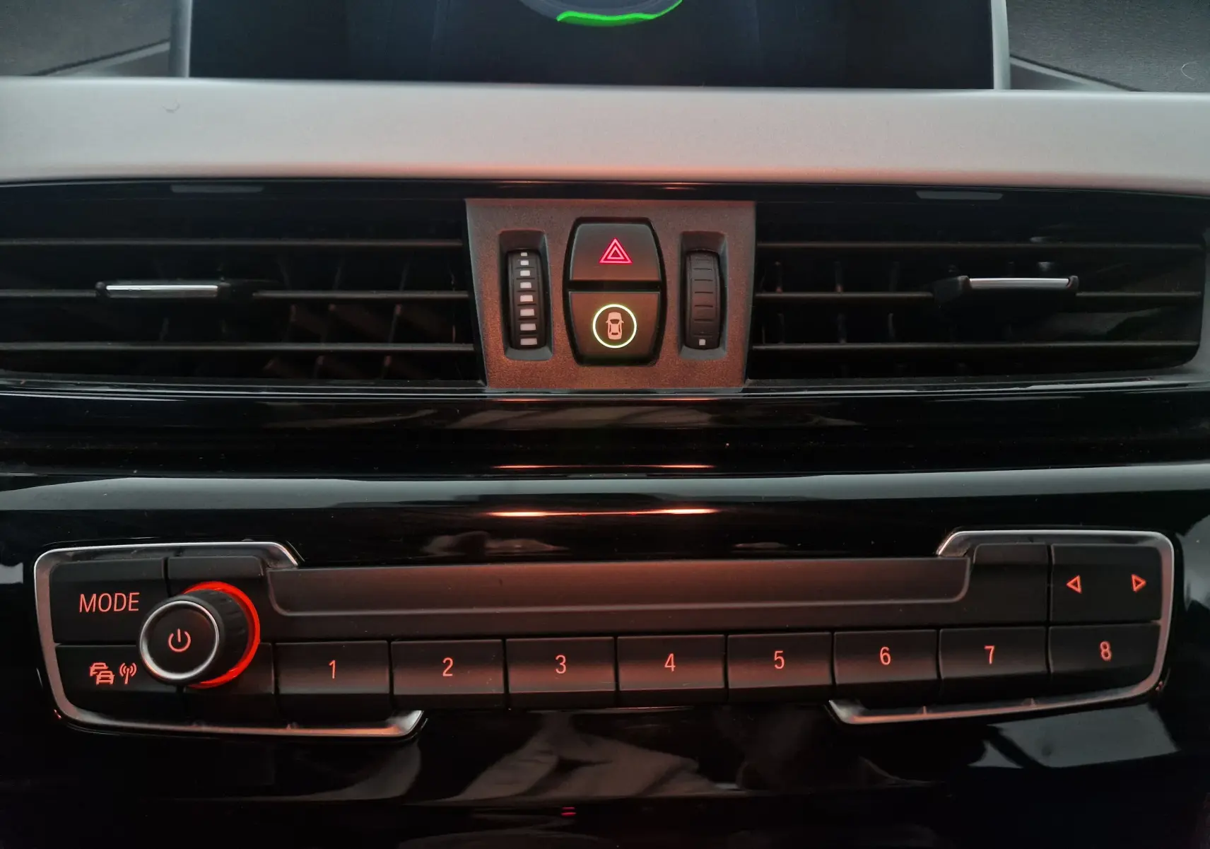 Gros plan sur la console centrale noire du BMW X2 gris clair, montrant les boutons de commande et les aérateurs.