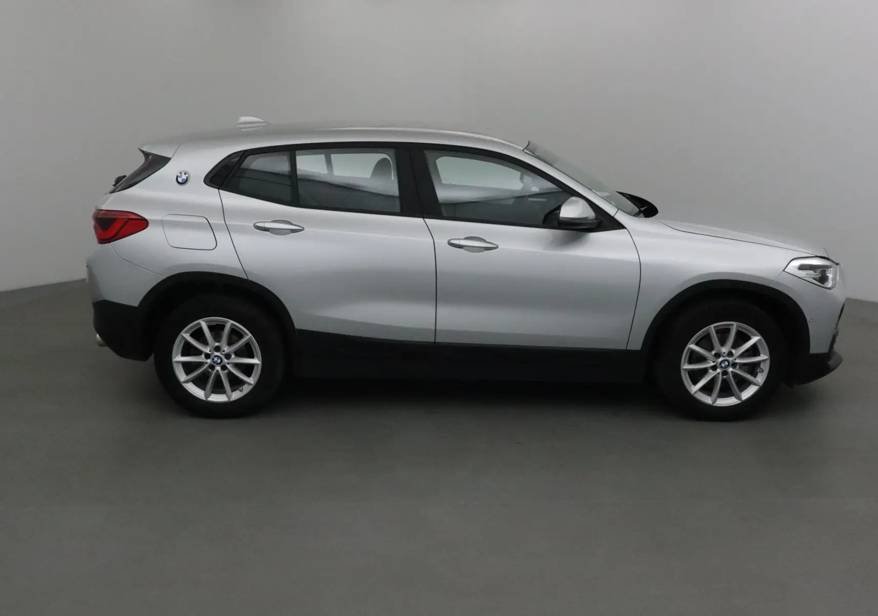 Vue de profil côté gauche d’un BMW X2 gris clair métal de 2018 avec jantes alliage et logo BMW visible à l’arrière.