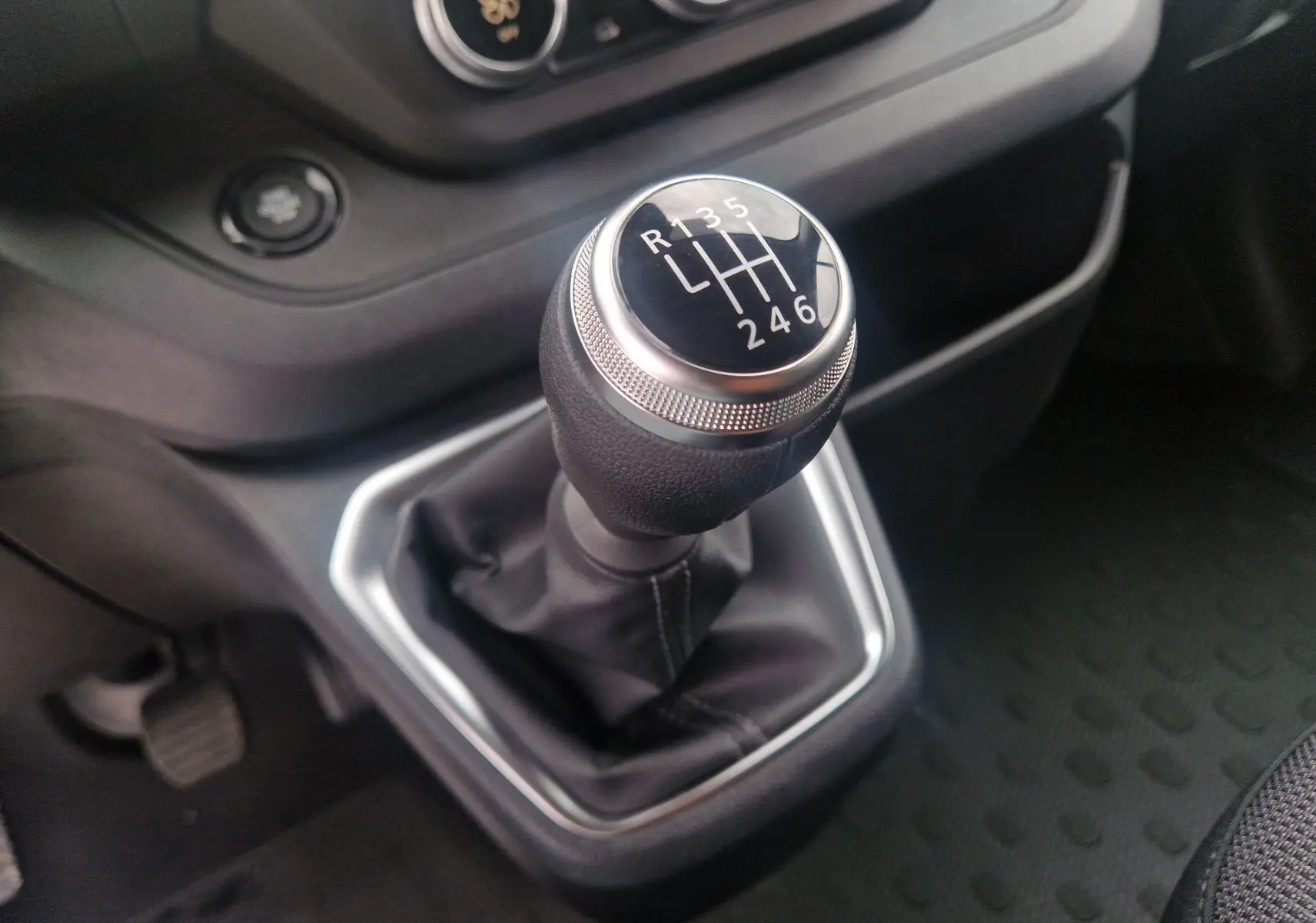Gros plan sur le levier de vitesses manuel du Renault Trafic Fourgon L1H1, intérieur noir avec console grise.