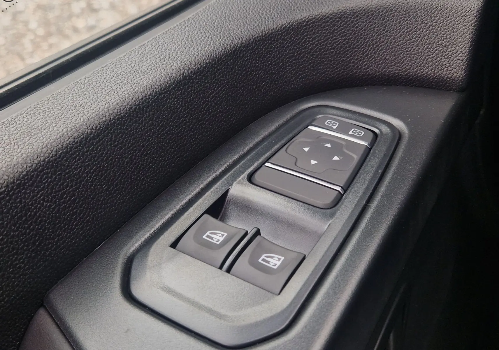 Gros plan sur les commandes électriques des vitres et des rétroviseurs côté conducteur du Renault Trafic Fourgon gris Highland.