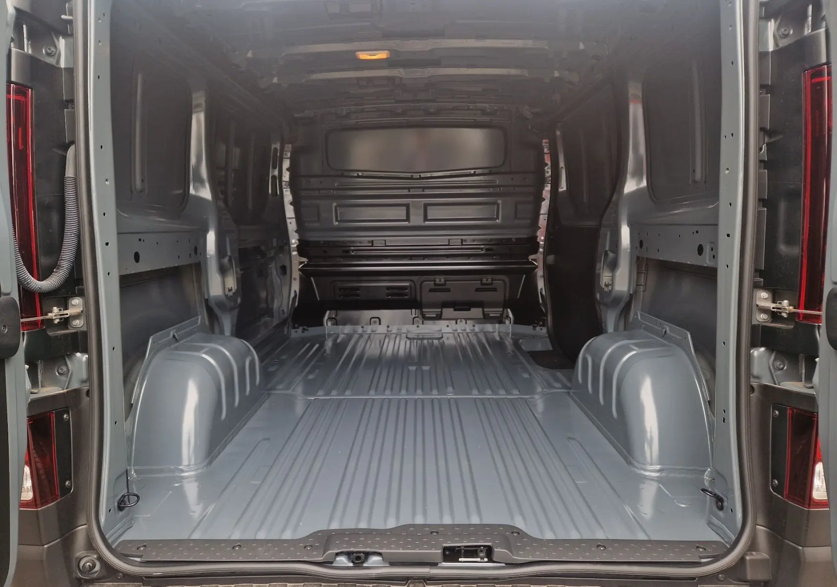 Vue arrière ouverte du Renault Trafic Fourgon gris Highland montrant l’espace de chargement vide et la cloison intérieure.