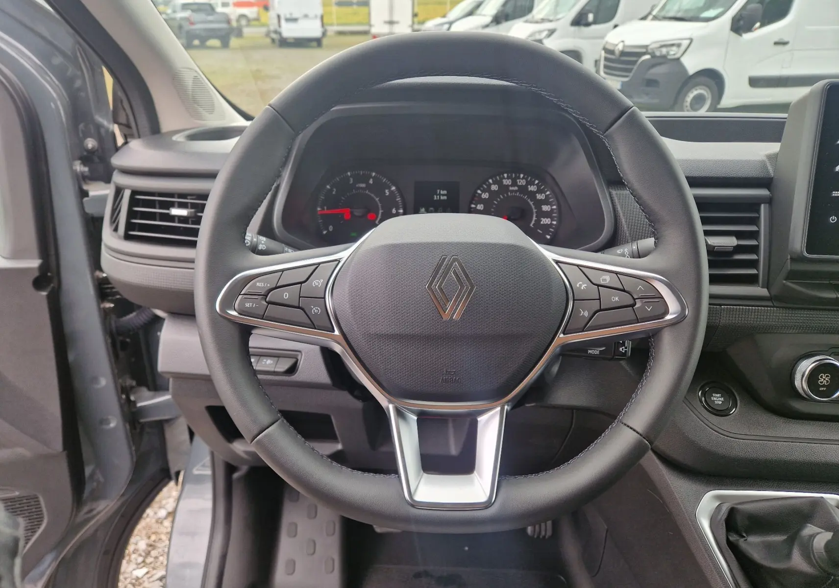 Vue intérieure centrée sur le volant noir du Renault Trafic Fourgon gris Highland avec tableau de bord et commandes visibles.