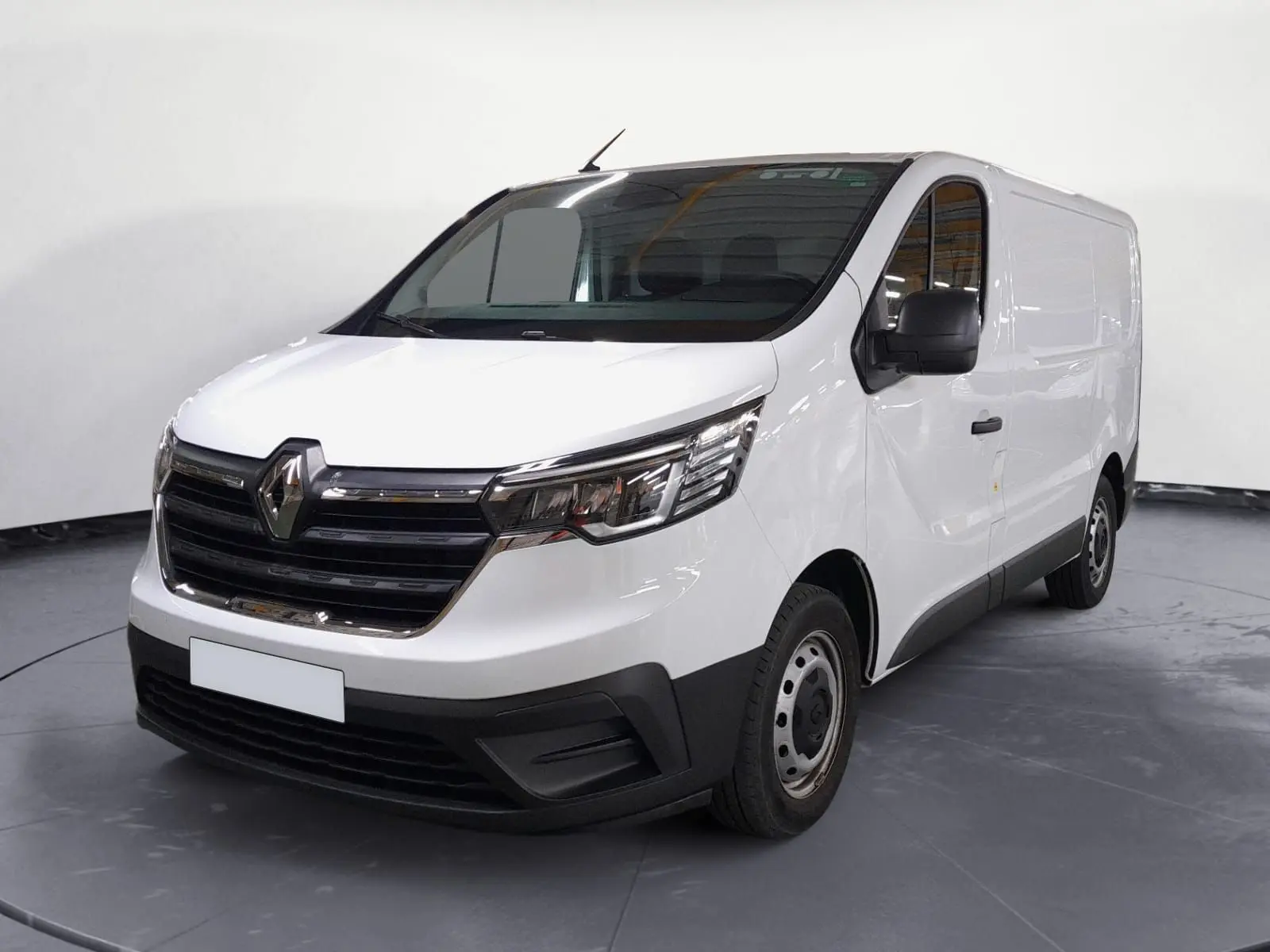 Vue 3/4 avant droite d’un Renault Trafic Fourgon blanc 2024 avec calandre noire et jantes acier simples.
