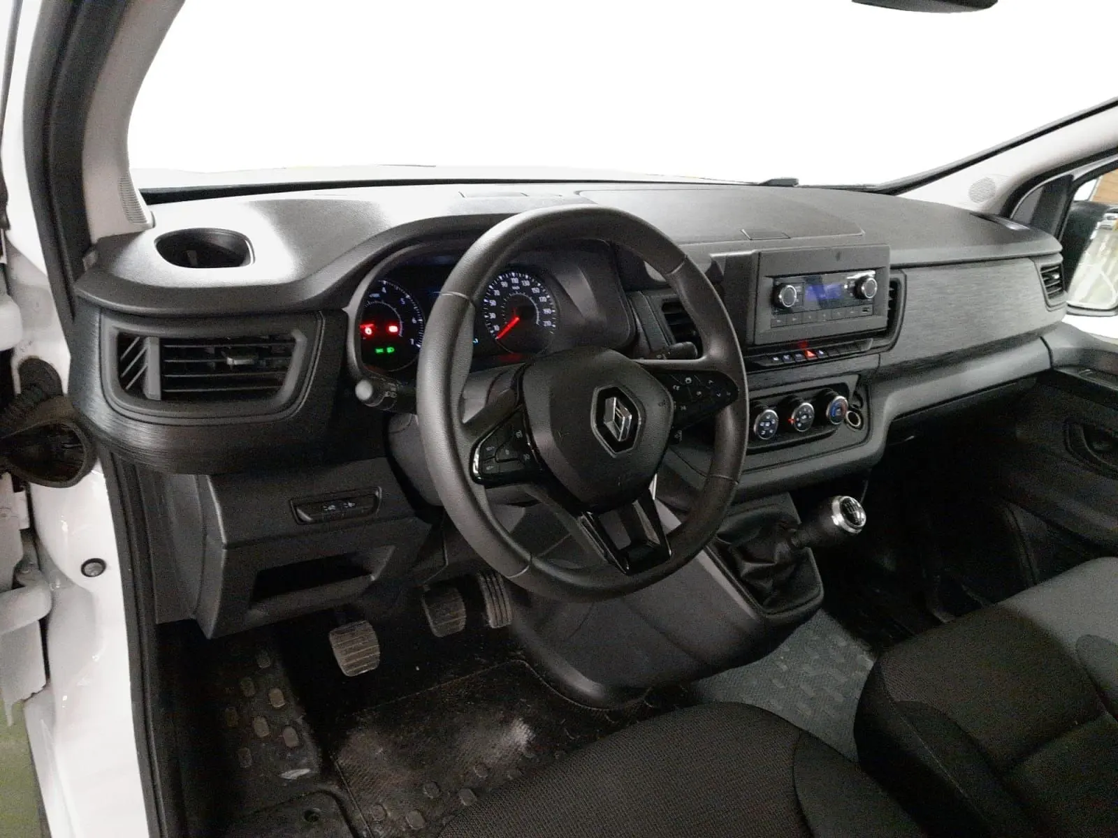 Gros plan sur la commande de lève-vitres et la poignée intérieure côté gauche du Renault Trafic Fourgon blanc, intérieur noir.