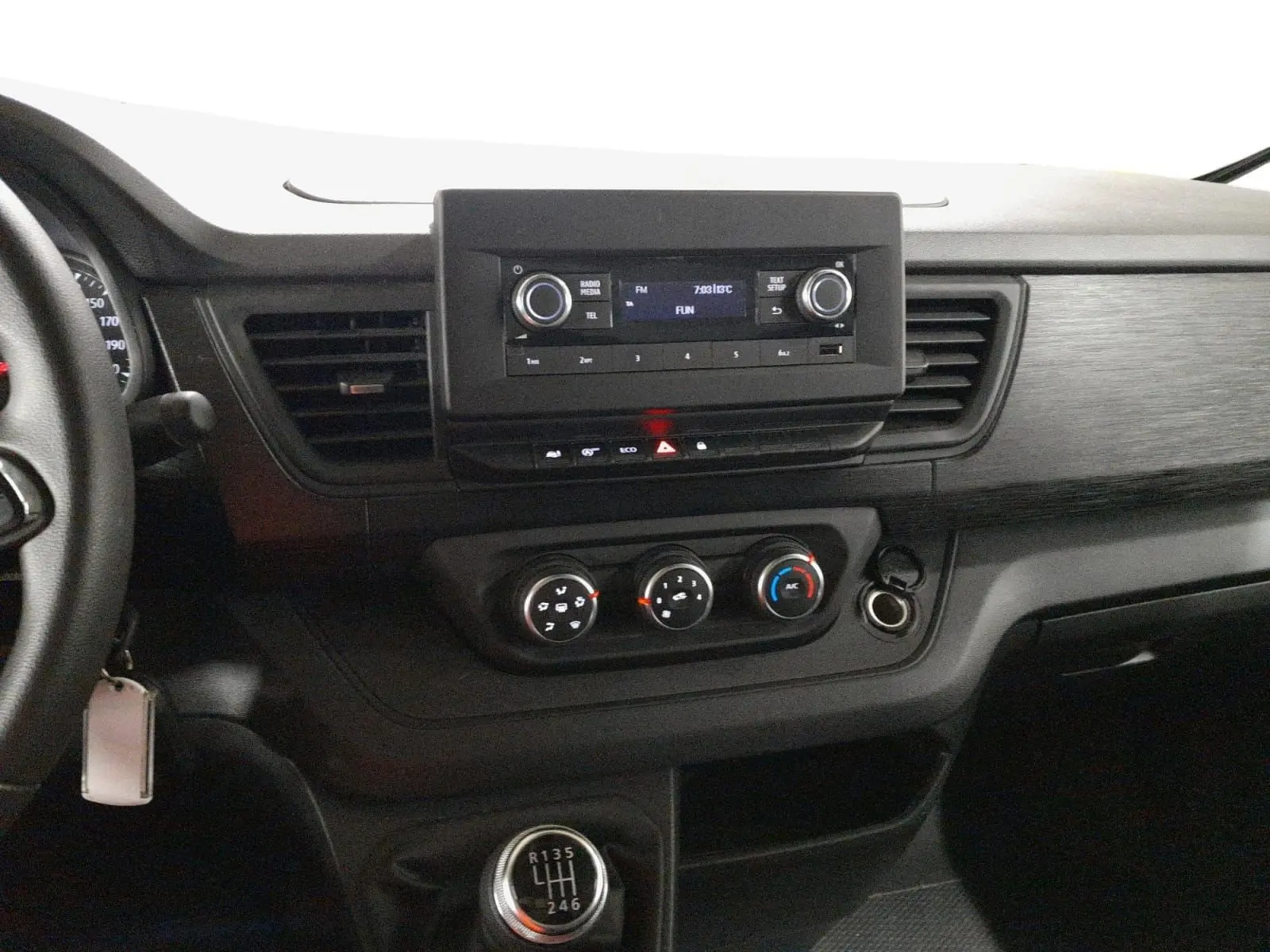 Vue intérieure côté conducteur du Renault Trafic blanc 2024, montrant la banquette noire et le tableau de bord moderne.