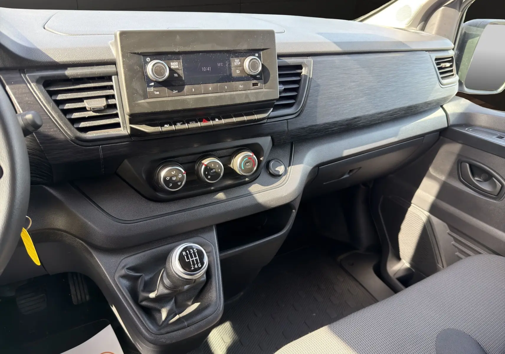 Vue intérieure côté passager du tableau de bord noir et de la boîte manuelle du Renault Trafic Fourgon blanc 2024.