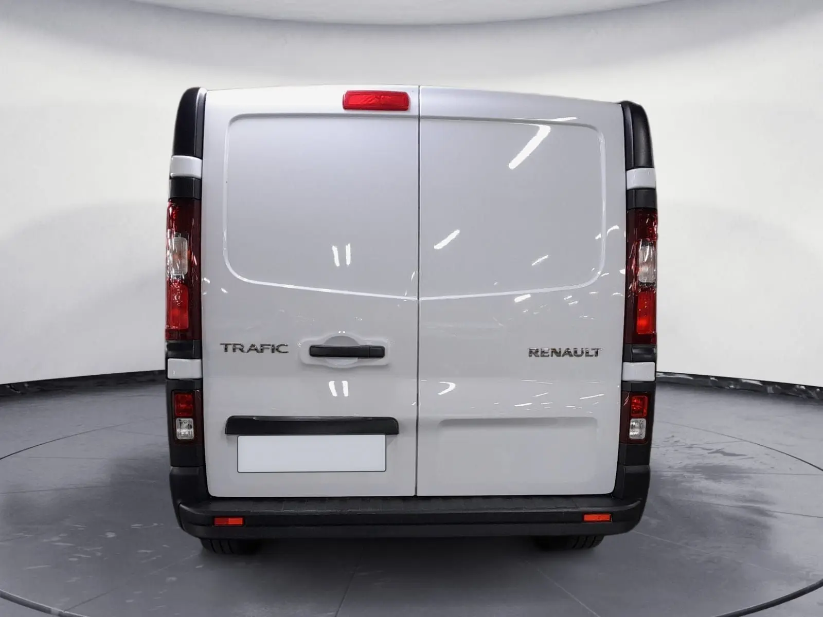 Vue arrière d’un Renault Trafic Fourgon blanc avec portes battantes et feux arrière verticaux visibles.