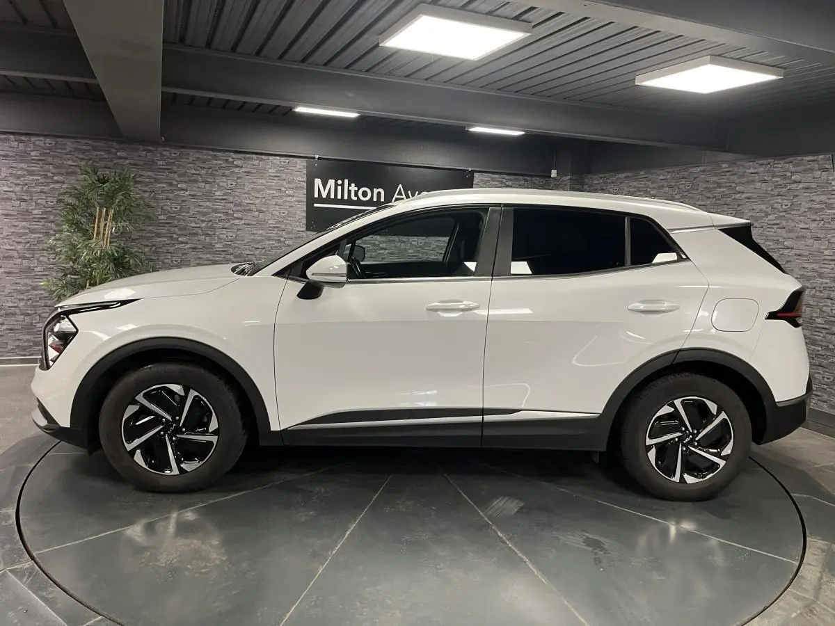 Profil droit du KIA Sportage blanc nacré 2022 avec jantes alliage noires et détails noirs laqués.