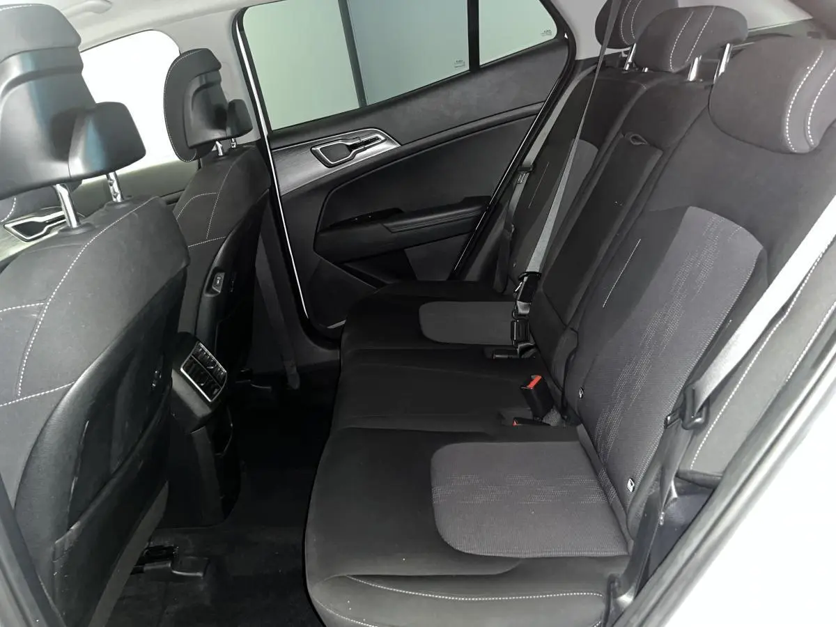 Vue intérieure côté gauche des sièges arrière noirs avec surpiqûres blanches du Kia Sportage blanc 2022.