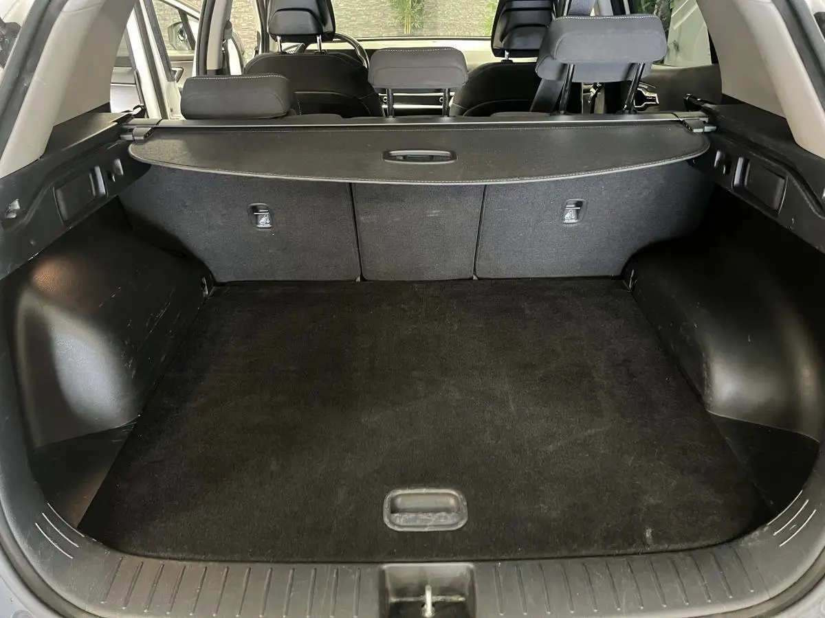 Coffre ouvert du Kia Sportage blanc, vue arrière montrant la plage arrière et les sièges noirs.