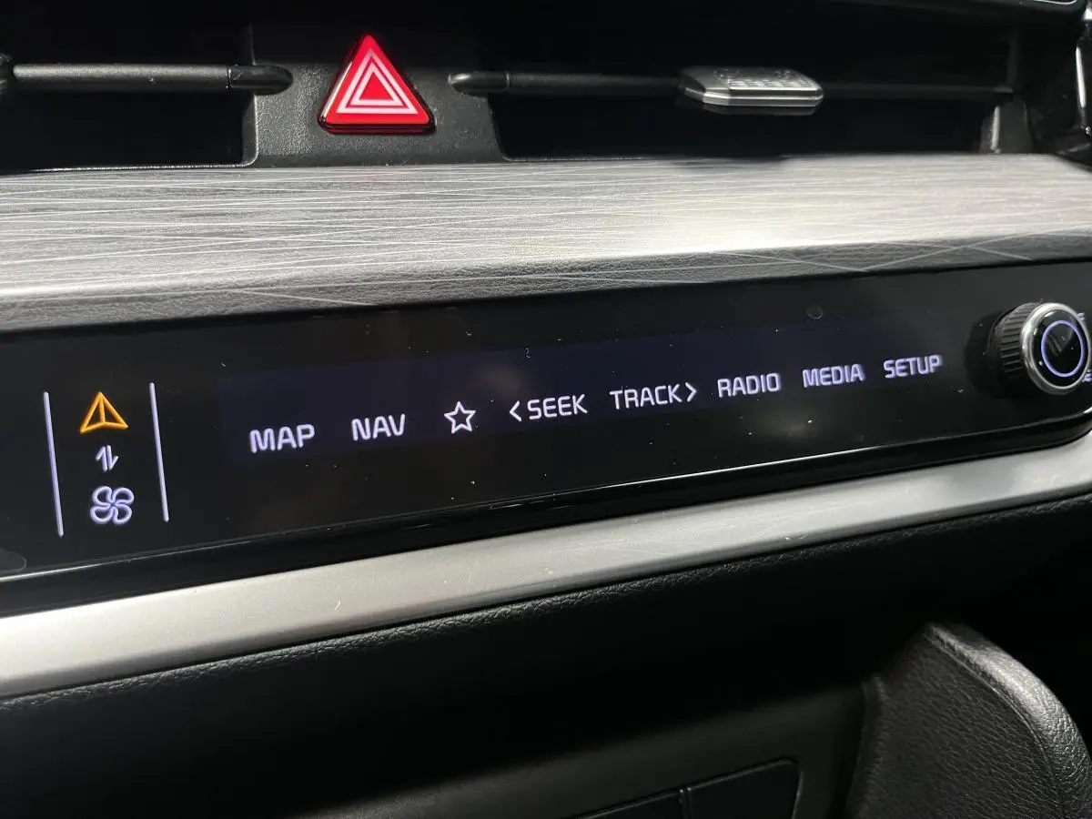 Détail de la console centrale du Kia Sportage 2022, écran tactile noir avec commandes multimédia et bouton rotatif.