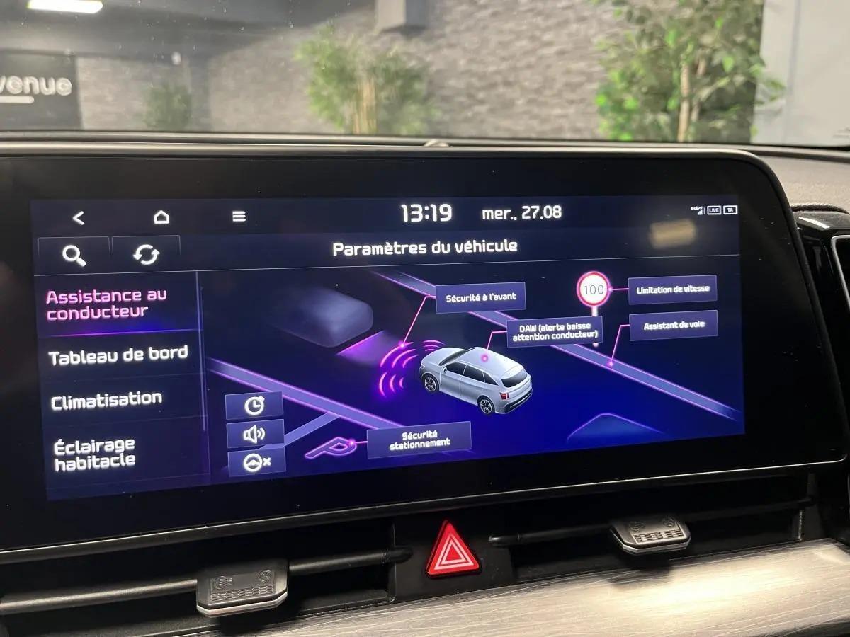 Écran tactile intérieur affichant les paramètres d’assistance du Kia Sportage blanc, vue de face.