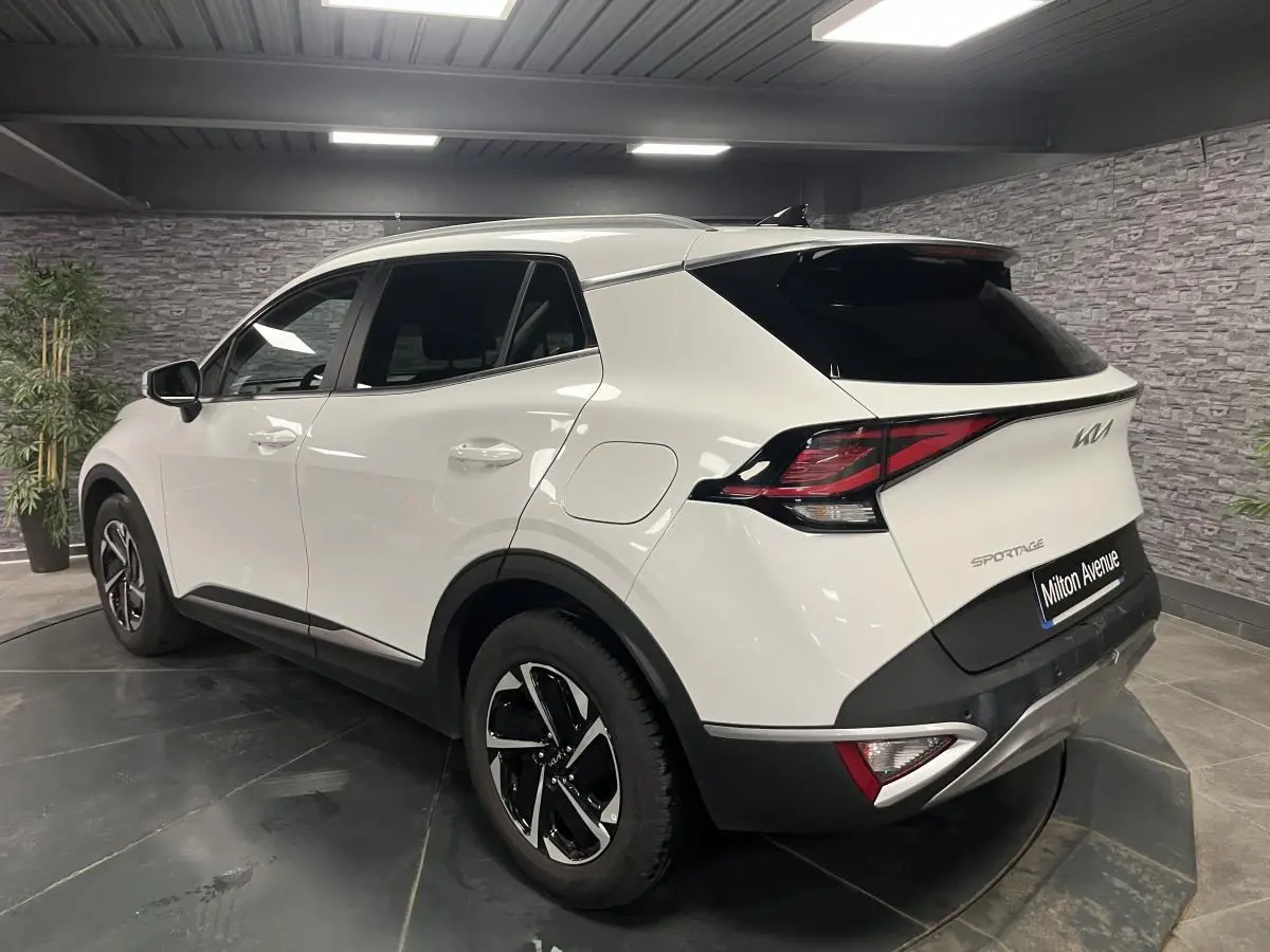 Vue 3/4 arrière droit du KIA Sportage blanc nacré avec jantes alliage 18 pouces et feux arrière LED.