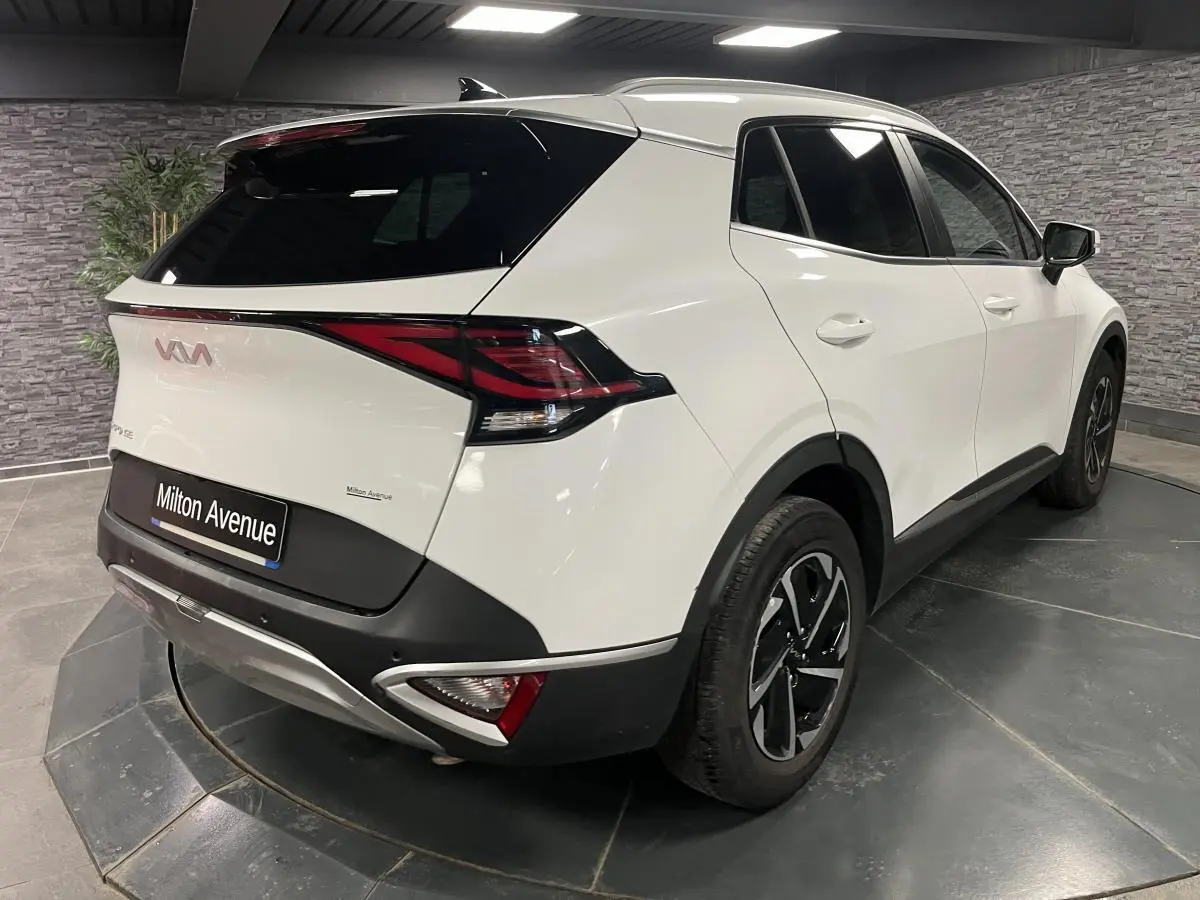 Vue 3/4 arrière droite du KIA SPORTAGE blanc nacré avec feux arrière LED et jantes alliage 18 pouces.