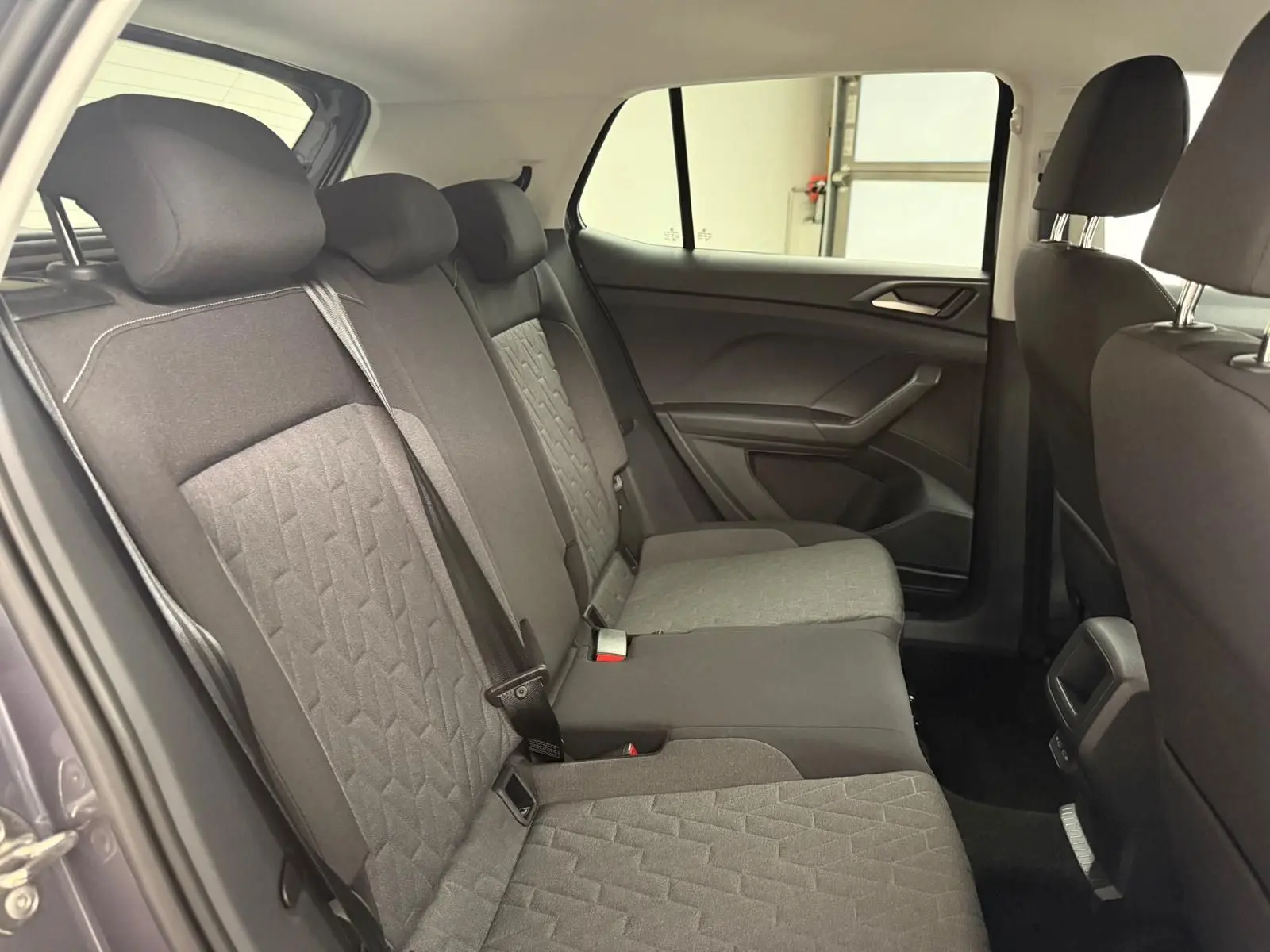 Vue intérieure des sièges arrière du Volkswagen T-Cross 2025 gris cendre, montrant les textures et ceintures de sécurité.