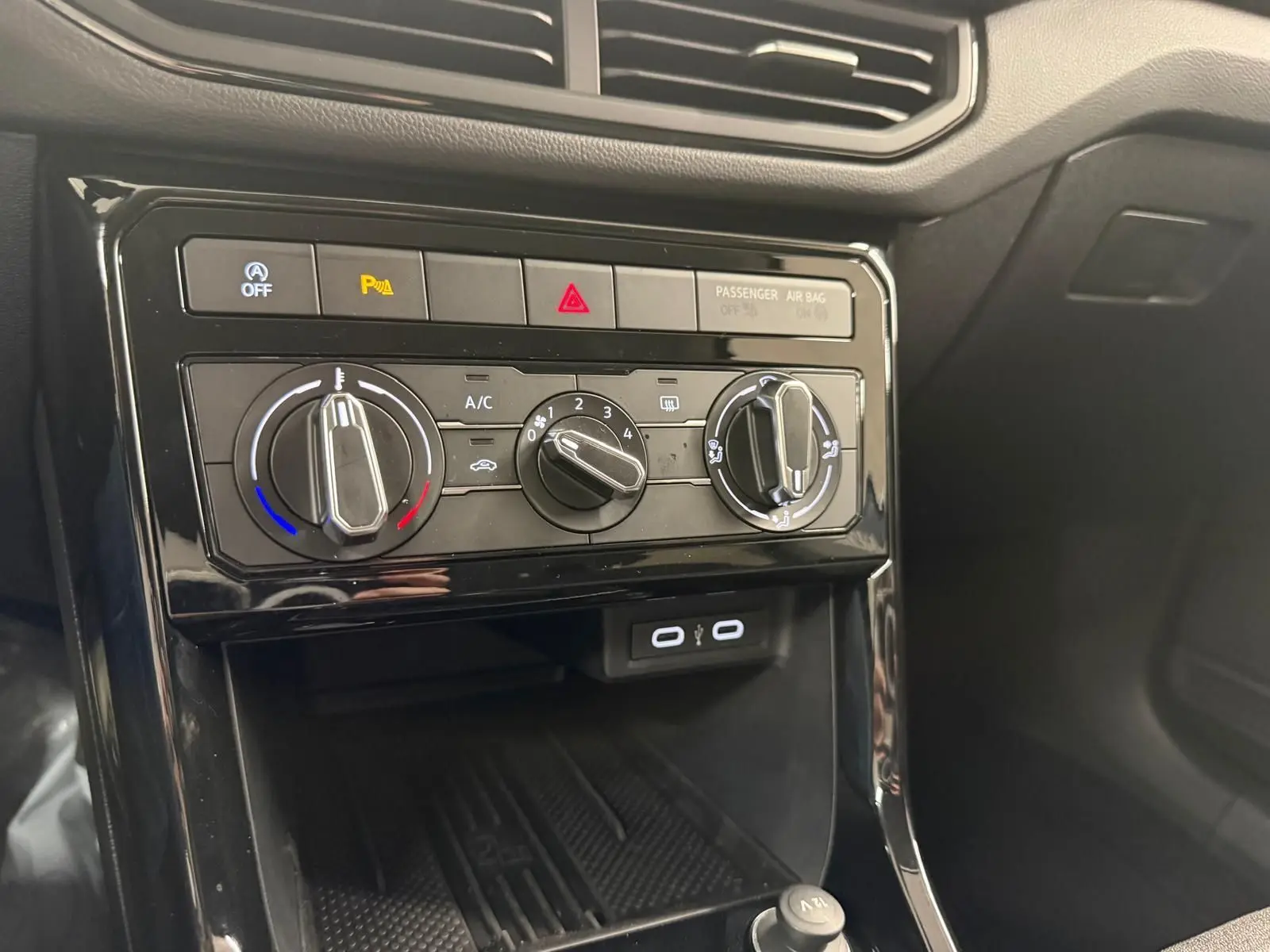 Gros plan sur la console centrale du Volkswagen T-Cross 2025, avec commandes climatisation et ports USB visibles.
