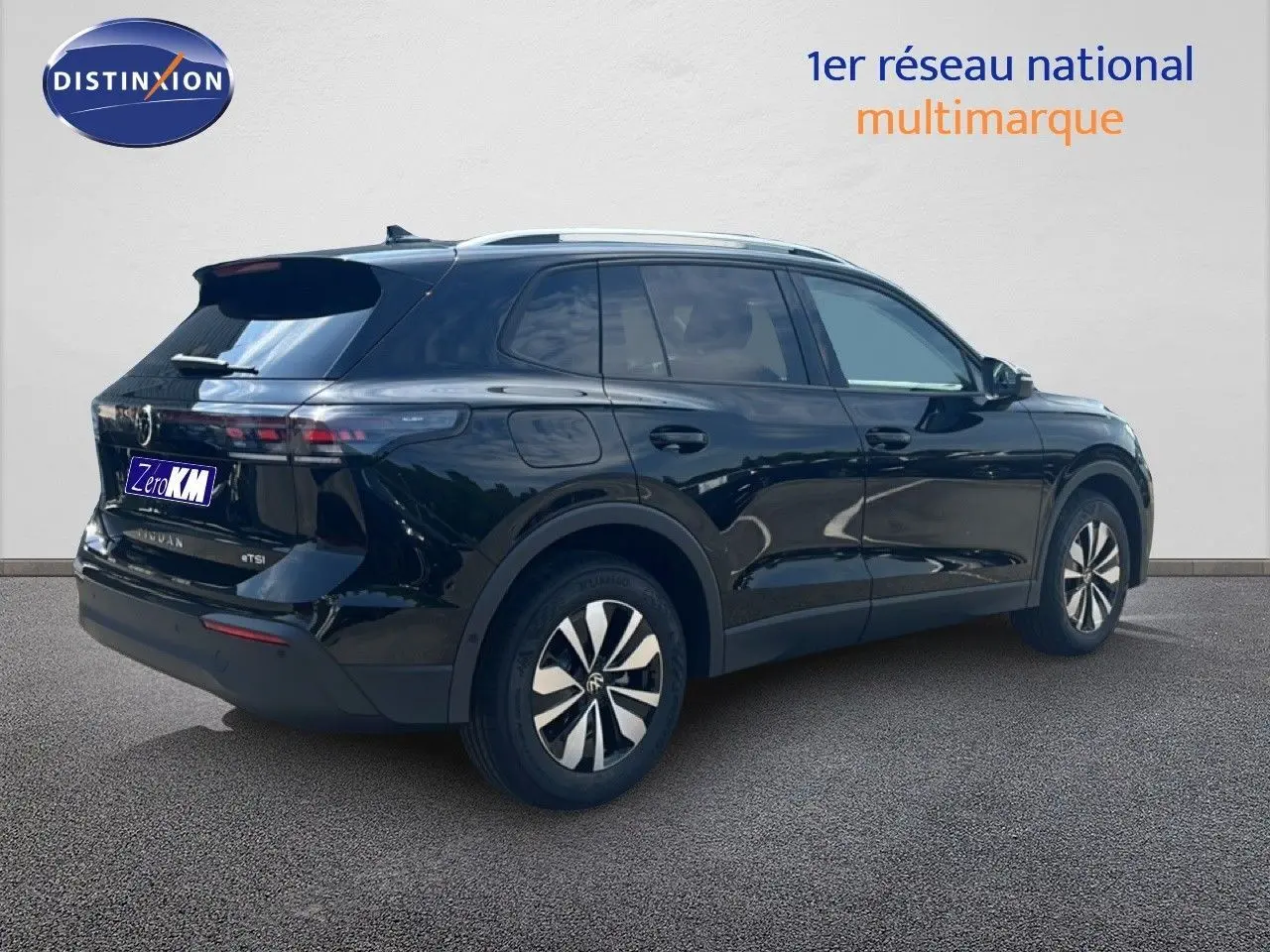 Vue 3/4 arrière droite d'un Volkswagen Tiguan noir Grenadilla métallisé avec jantes bicolores et toit argenté.