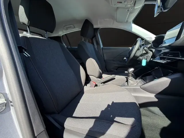 Vue intérieure côté gauche de la Peugeot 208 100 ch Style 2025, sièges tissu gris, volant cuir multifonctions et tableau de bord.