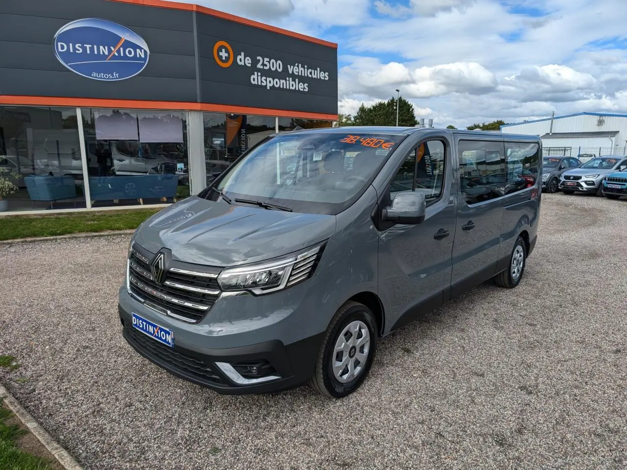 Renault Trafic Fourgon gris Urban en 3/4 avant droit, avec calandre chromée et vitres latérales teintées.